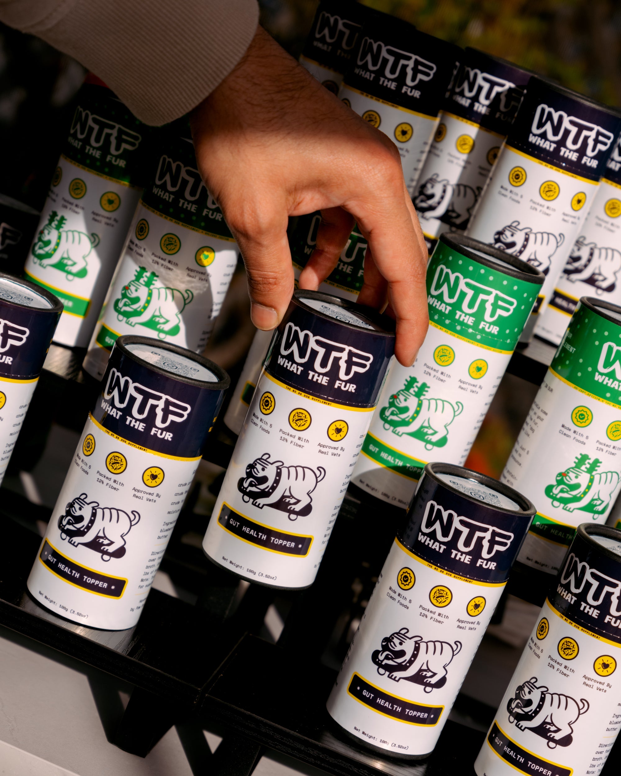 Hand picking up What The Fur Gut Health Topper, a natural dog supplement made with clean ingredients like beef, blueberries, apples, kale and peanut butter to support digestion and gut health.