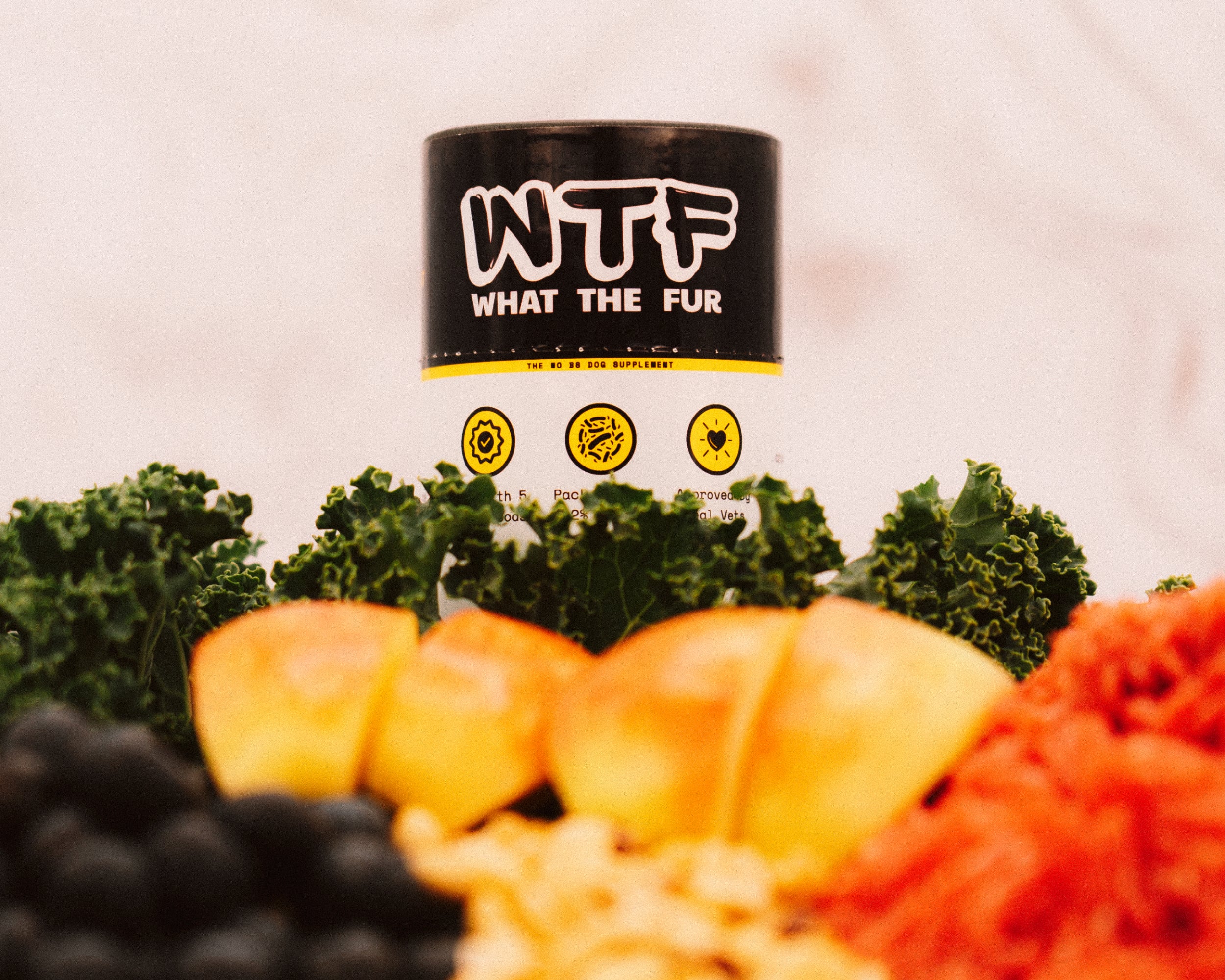 What The Fur dog supplement topper surrounded by natural superfoods like kale, apples, and blueberries. Supports gut health, calm, and skin relief.